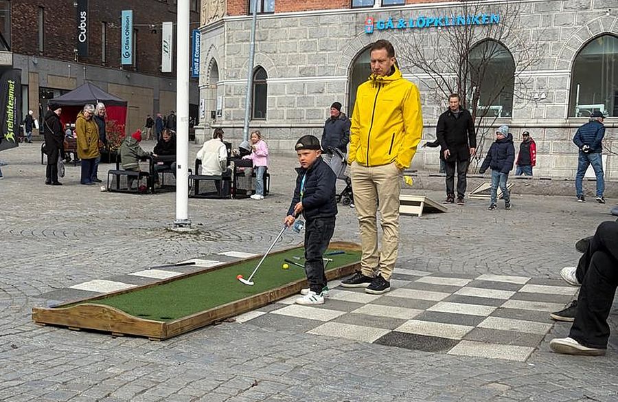 Barn och vuxen spelar Kubbgolf på stadstorget