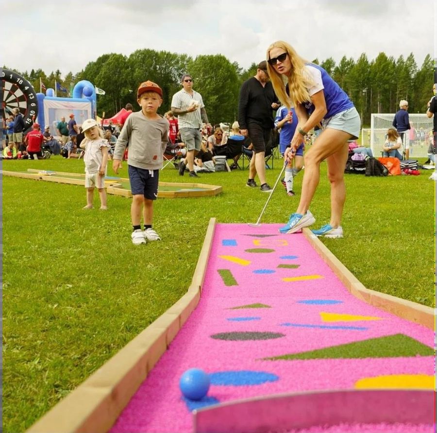 Barn och vuxen spelar minigolf på festivalområde